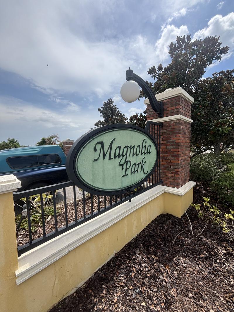 The same entrance sign after washing, the cap white again and the stucco an even yellow