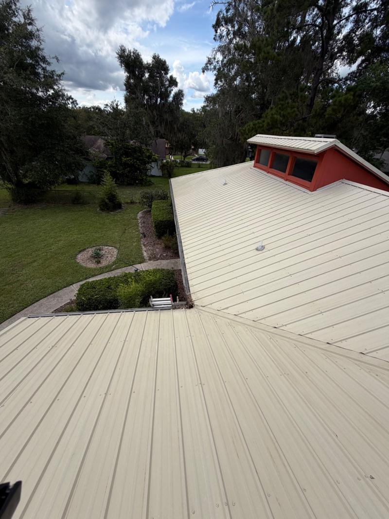 The same metal roof slope after soft washing, the panels an even pale cream