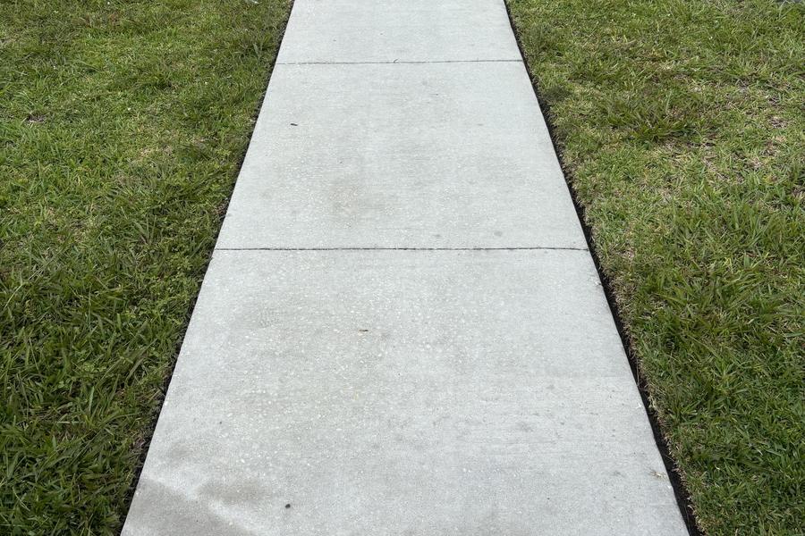 The same walkway after pressure washing, concrete returned to an even clean grey